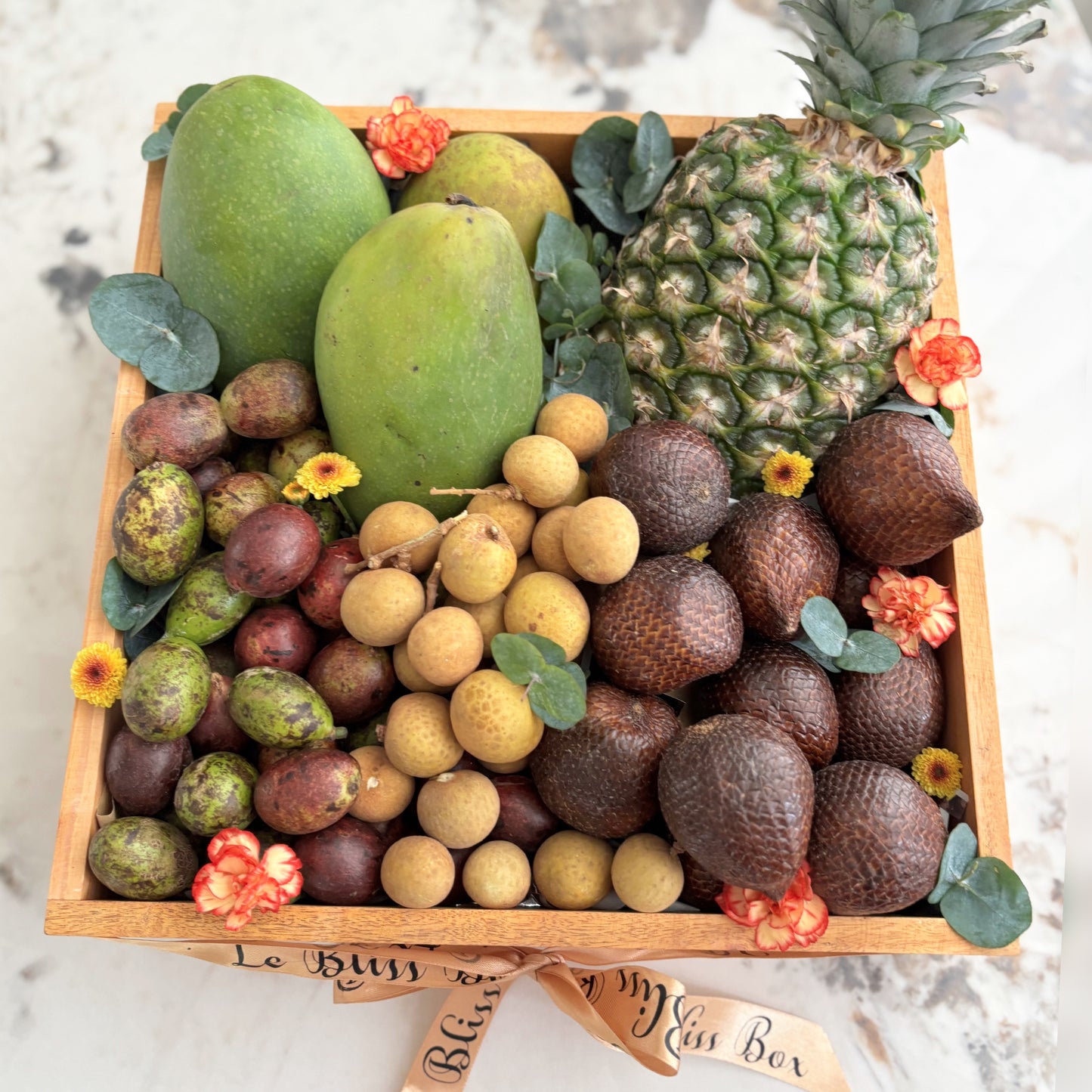 Assorted fruits in a wooden box with 'Le Bliss Box' branding on a marble surface. parcel buah surabaya, parcel buah jakarta. tropical fruit hamper jakarta, surabaya, cirebon