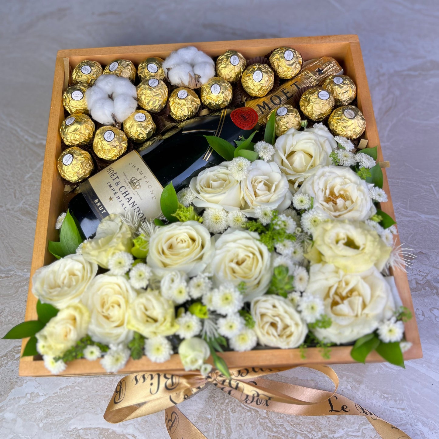 Moet Hamper, Gift box with white flowers, chocolates, and a bottle of champagne on a light background. Wine hamper jakarta, surabaya, tangerang by le bliss