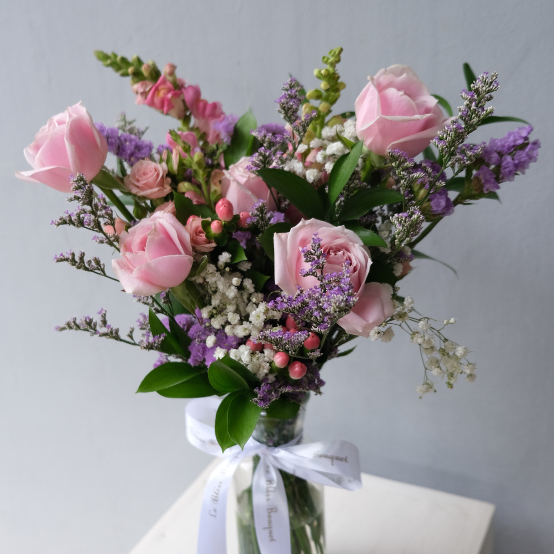 soft rose bouquet in a glass bottle vase with pastel fillers – elegant flower arrangement for table decor and delivery in Jakarta, Cirebon, and Bintaro.