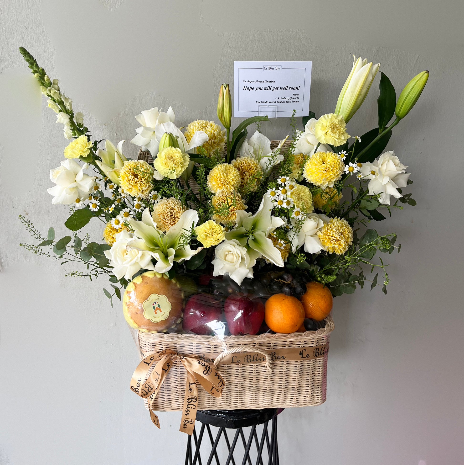 Parcel buah eksklusif berisi white lily Playa Blanca dan buah segar dalam keranjang rotan mewah — White Lily Grand Fruit Parcel dari Le Bliss Surabaya.
