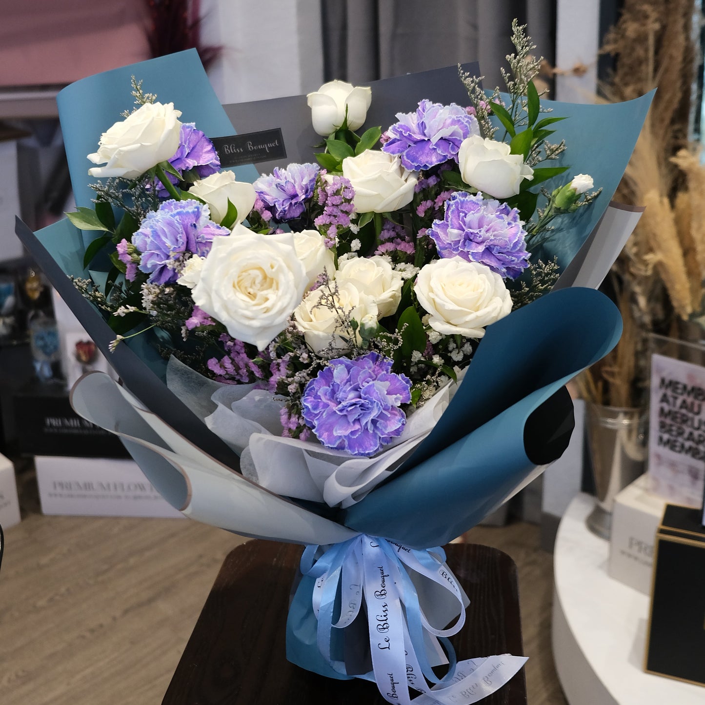 Bouquet of flowers with a blue ribbon on a table. blue carnation dyed bouquet by le bliss bouquet. florist jakarta, florist surabaya, florist cirebon