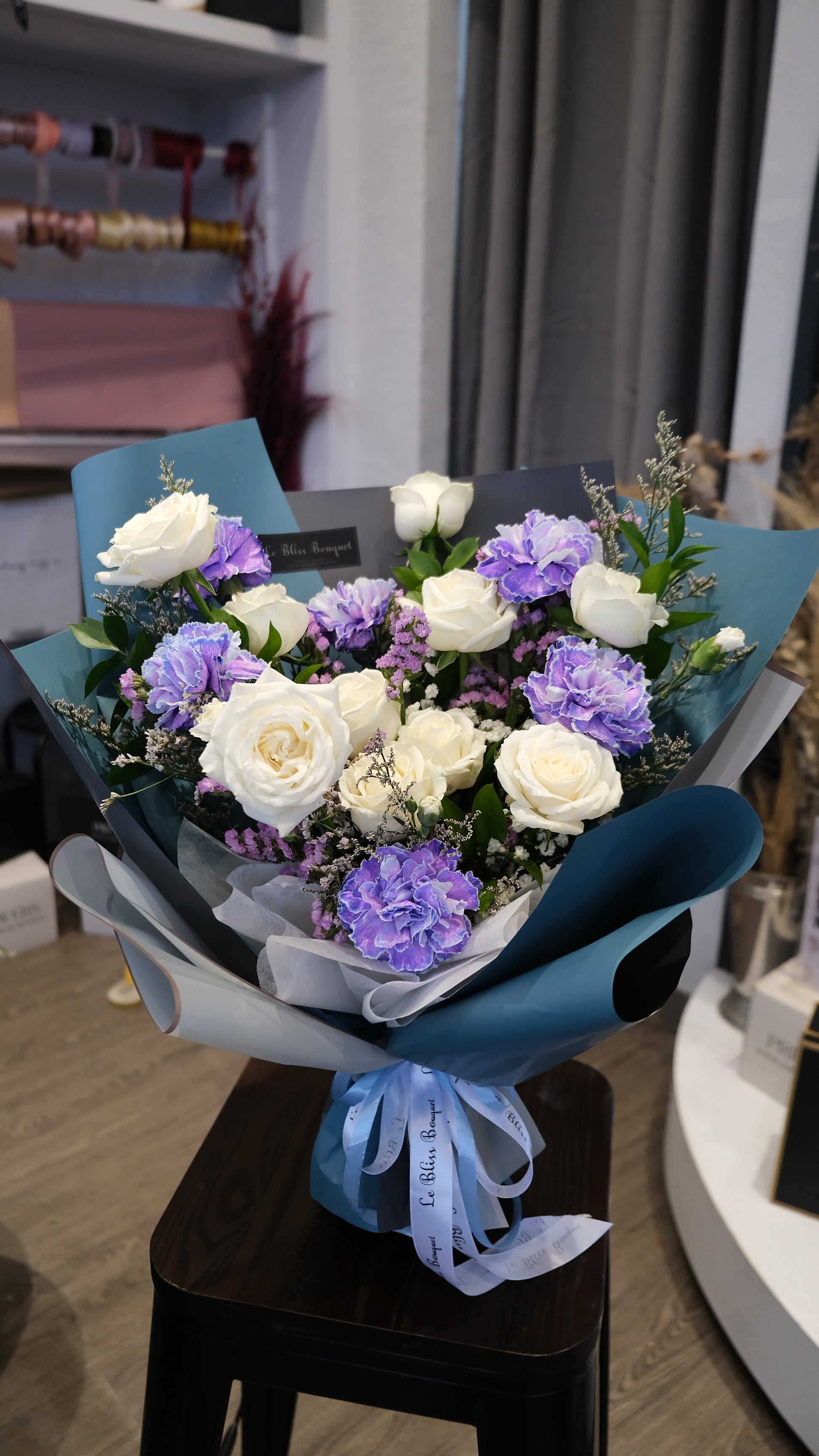 Bouquet of flowers with a blue ribbon on a table. blue carnation dyed bouquet by le bliss bouquet. florist jakarta, florist surabaya, florist cirebon, toko bunga jakarta, gift for him jakarta