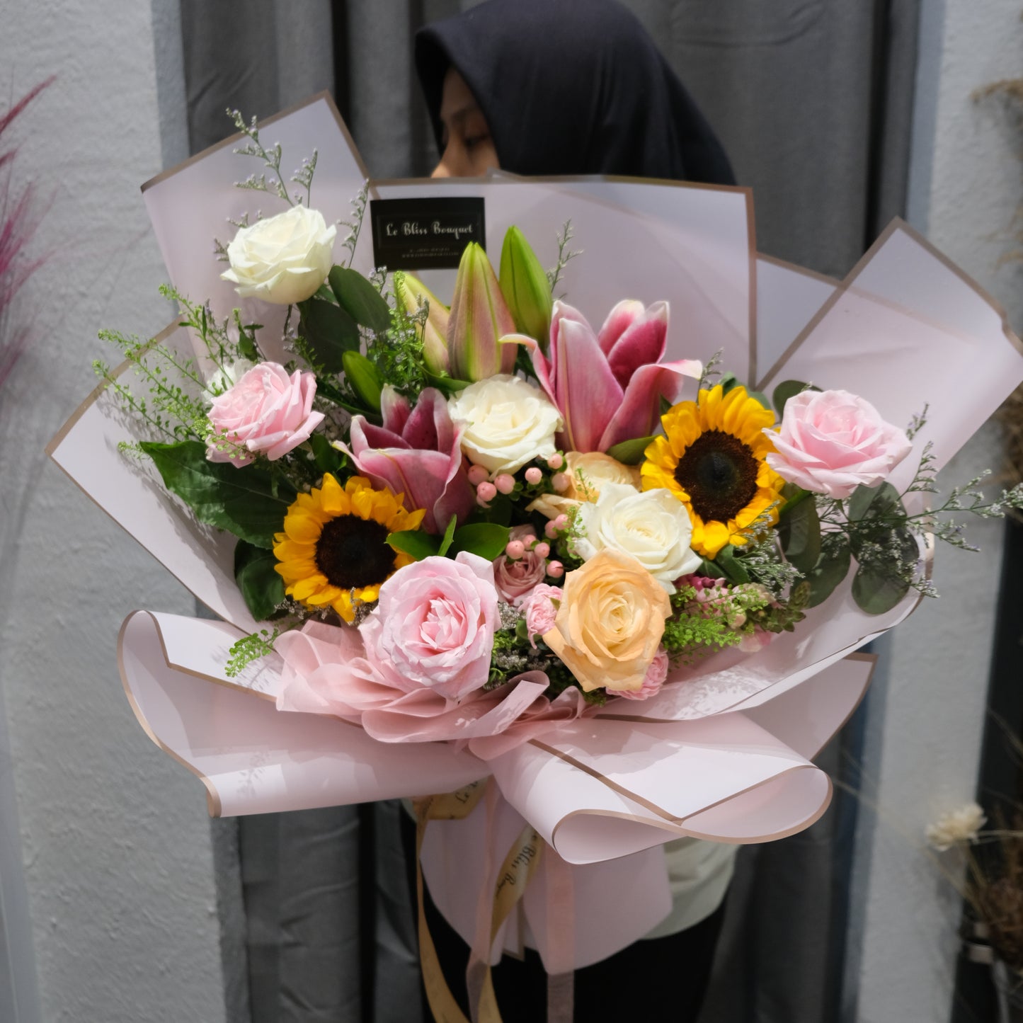 Bouquet of flowers with pink and yellow flowers on a white surface. sunflower lily pink bouquet by le bliss. florist surabaya, florist jakarta, florist cirebon