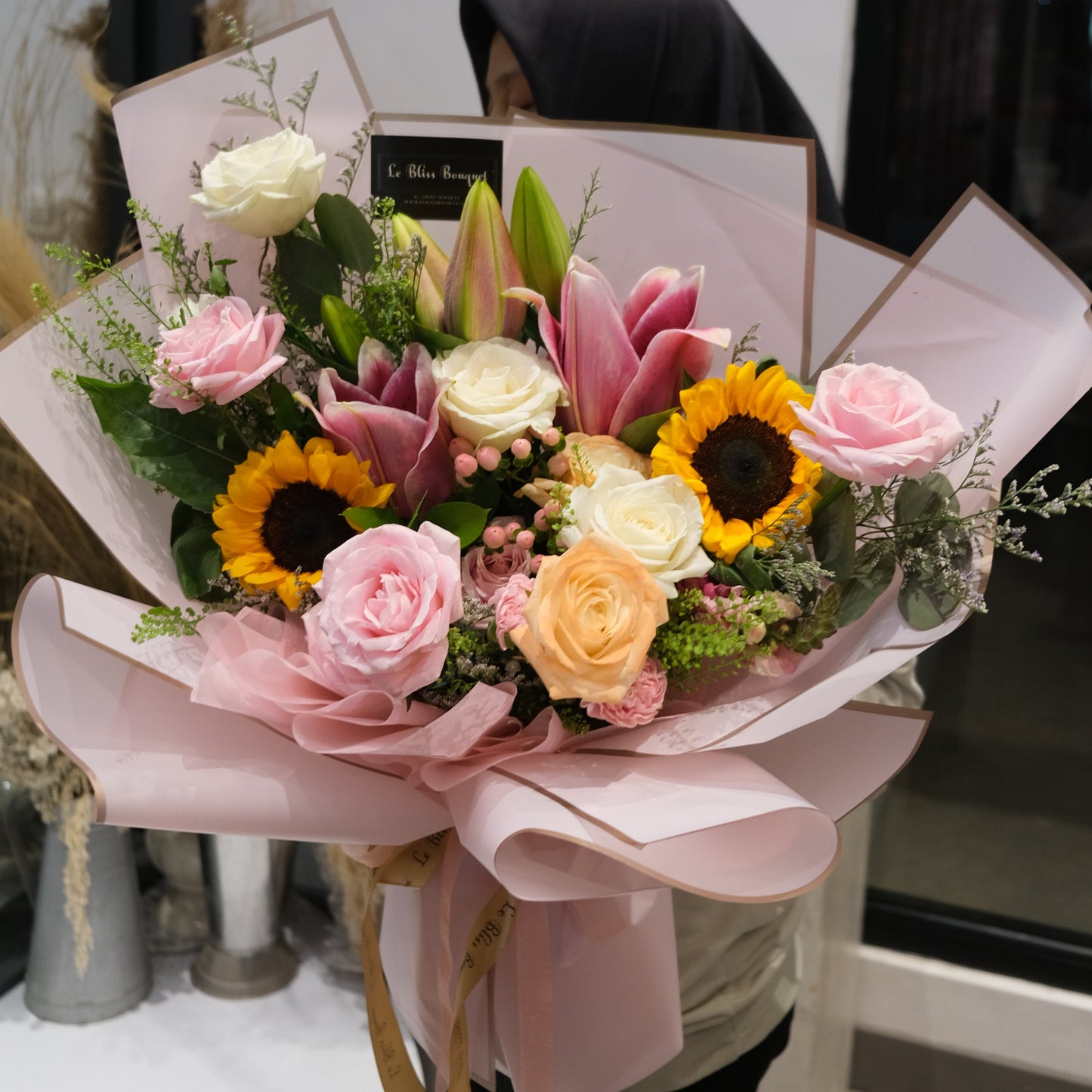 Bouquet of flowers with pink and yellow flowers on a white surface. sunflower lily pink bouquet by le bliss. florist surabaya, florist jakarta, florist indonesia