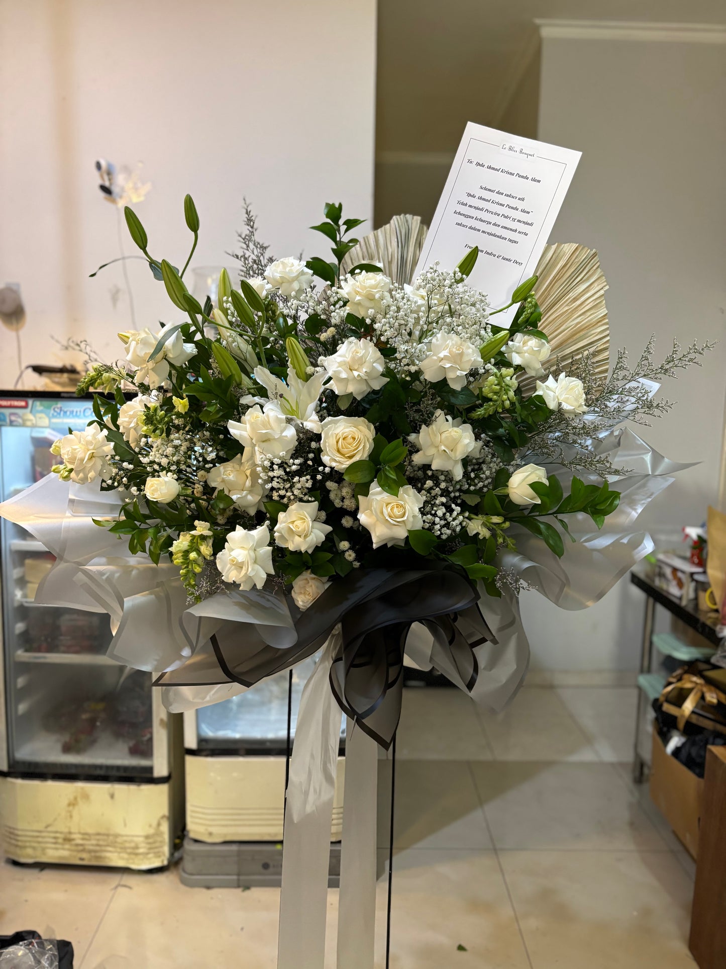 Bouquet standing flower of white flowers with greenery on a stand in a store setting. florist surabaya, standing flower jakarta, standing flower surabaya