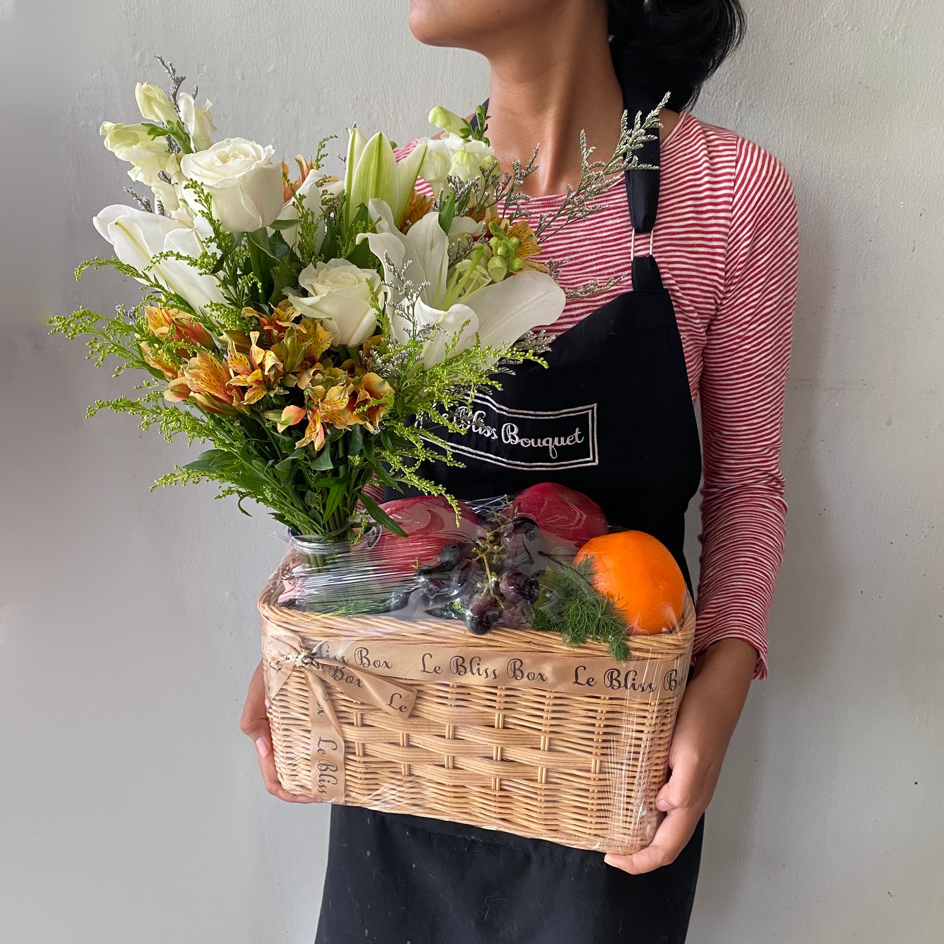 Parcel buah Surabaya dengan bunga white lily elegan dan buah segar dalam keranjang rotan — White Lily Fruit Parcel dari Le Bliss.