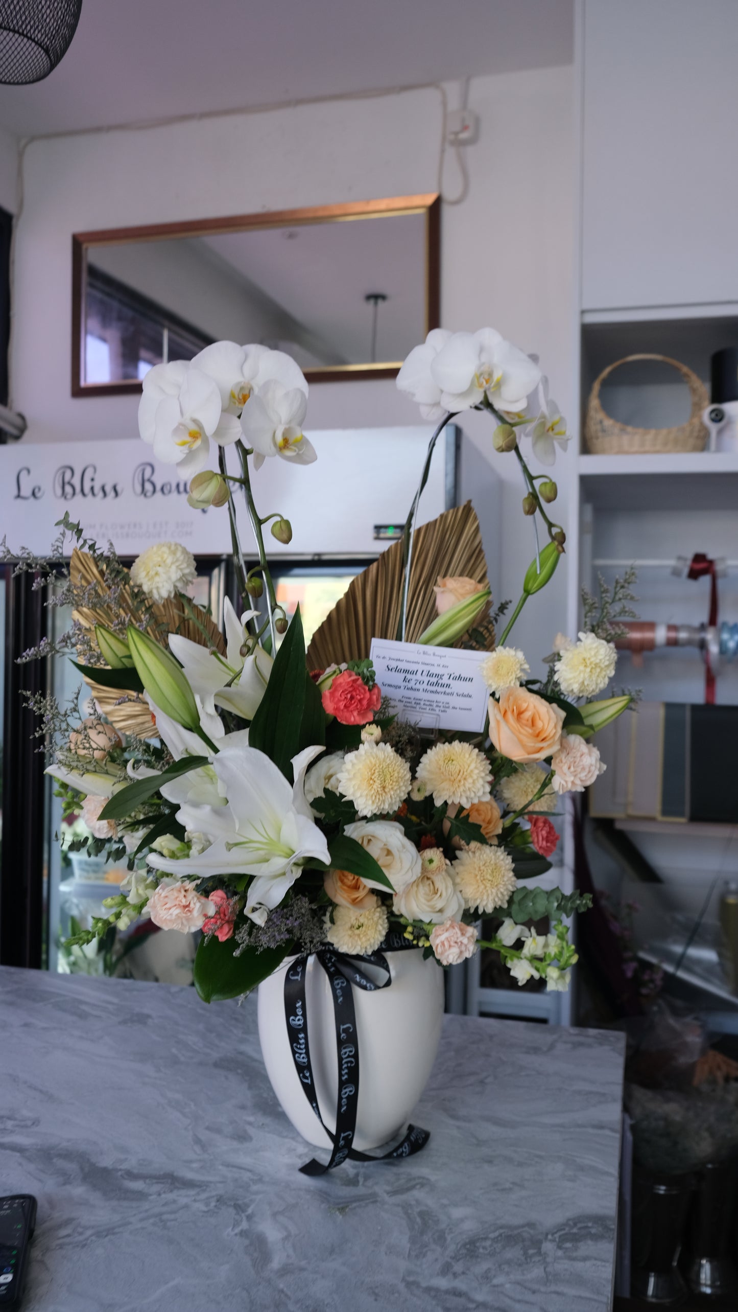 Double orchid vase with white lilies and orange flowers from Le Bliss Bouquet florist Surabaya, available for delivery to Cirebon, Jabodetabek, Sidoarjo, Gresik, and Majalengka.