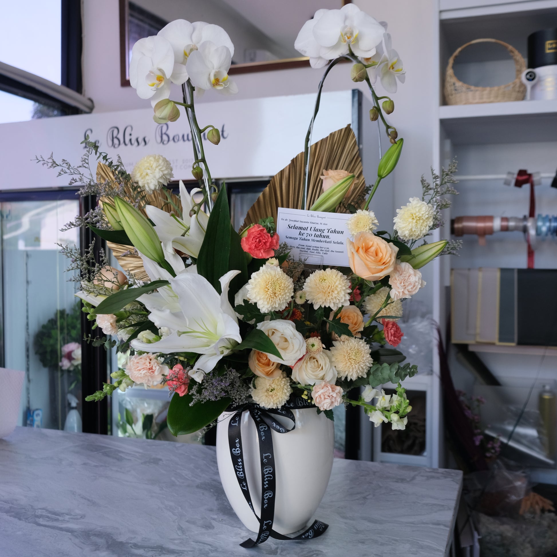 Double orchid vase with white lilies and orange flowers from florist Surabaya, available for delivery to Cirebon, Jabodetabek, Sidoarjo, Gresik, and Majalengka.
