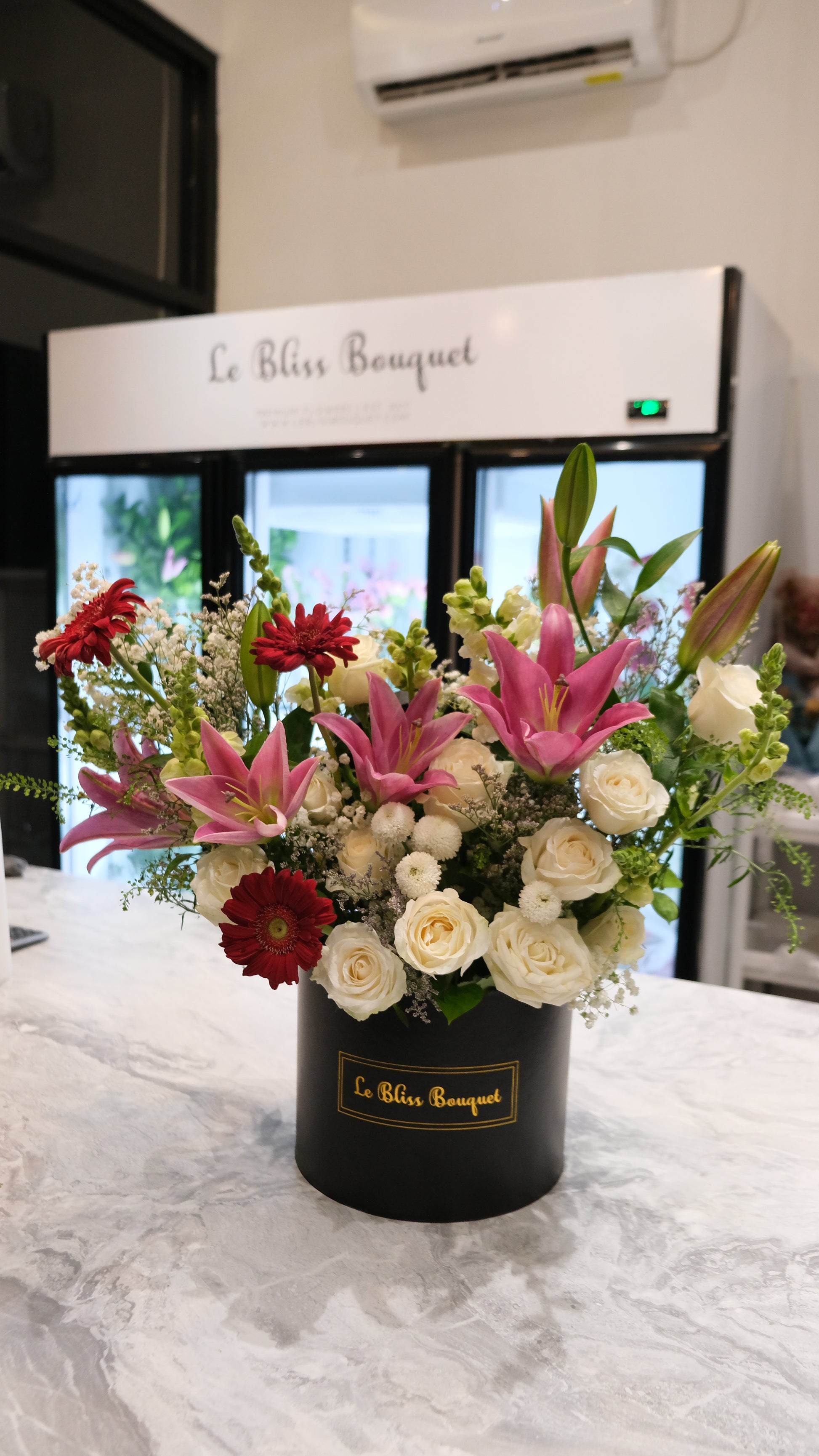 Floral arrangement in a black box with 'Le Bleu Bouquet' branding, against a marble wall. Pink Lily White Rose Grand Bloombox – Toko Bunga Premium. florist jakarta, florist surabaya, florist cirebon, gresik, Sidoarjo, tangerang. le bliss bouquet