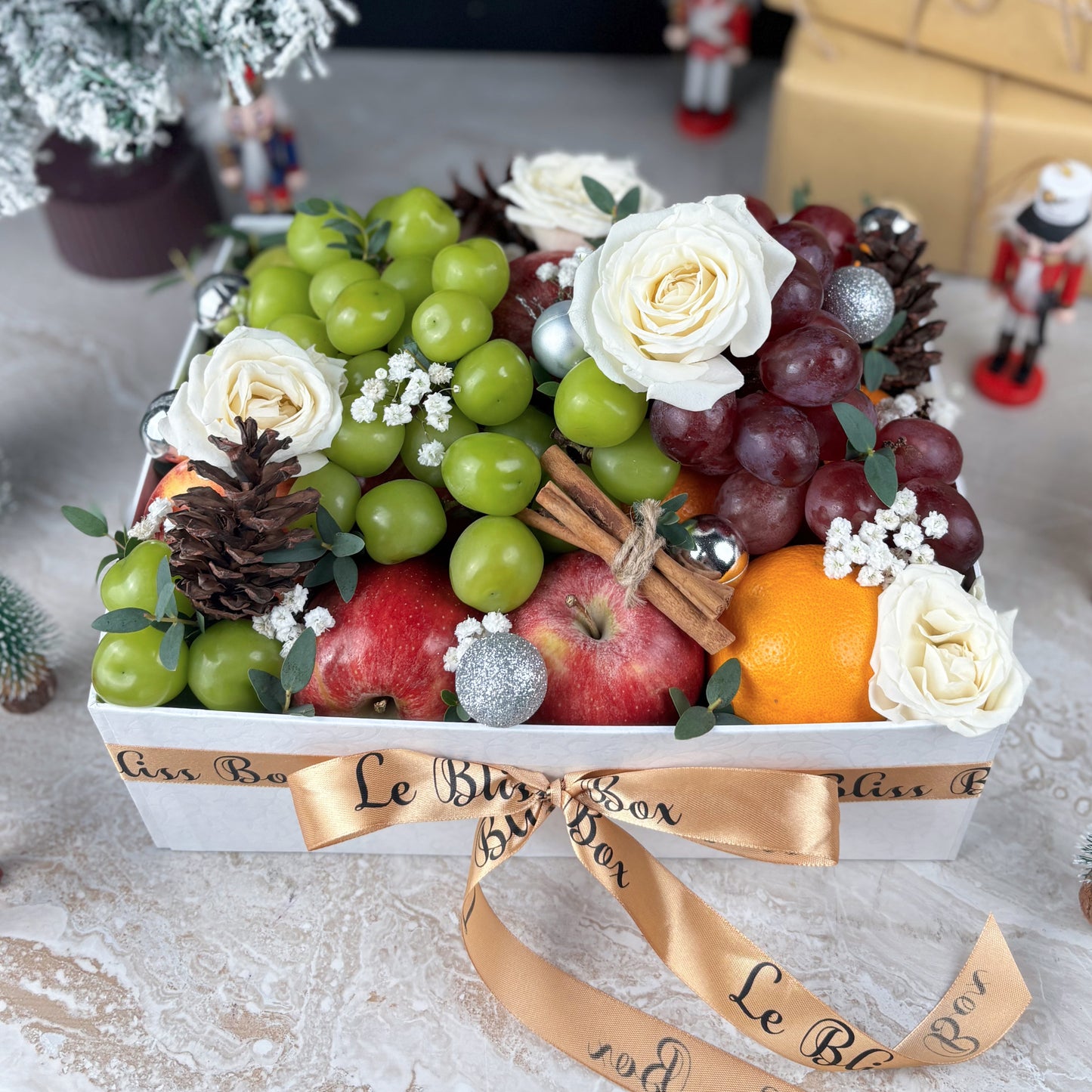 Fruit and flower arrangement in a decorative box with a ribbon, on a textured surface. parcel buah natal jakarta, parcel natal surabaya