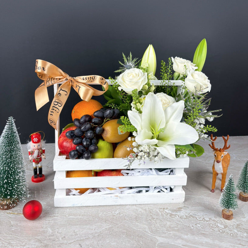 Fruit and flower arrangement in a white crate with decorative items on a dark background. Shop the best Christmas hamper in Jakarta, Tangerang, Cirebon & Surabaya. Le Bliss Bouquet’s Blooming White Crate Fruit Parcel blends beauty & premium fruits.