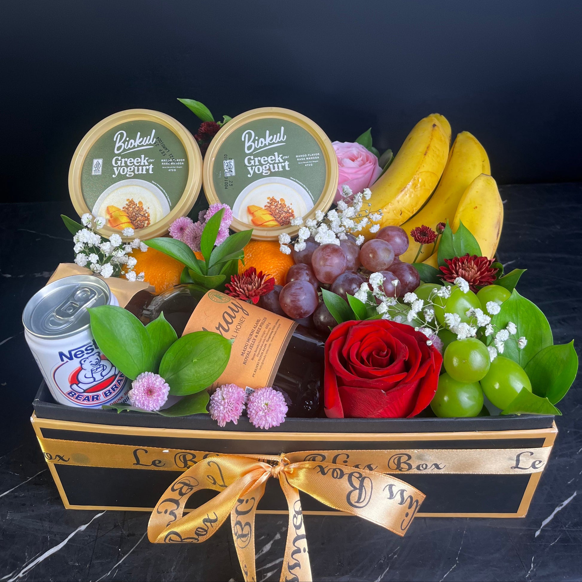 Fruit and yogurt basket with a red rose on a dark background. yogurt, honey, bear brand, banana, orange fruit hamper surabaya, jakarta, cirebon