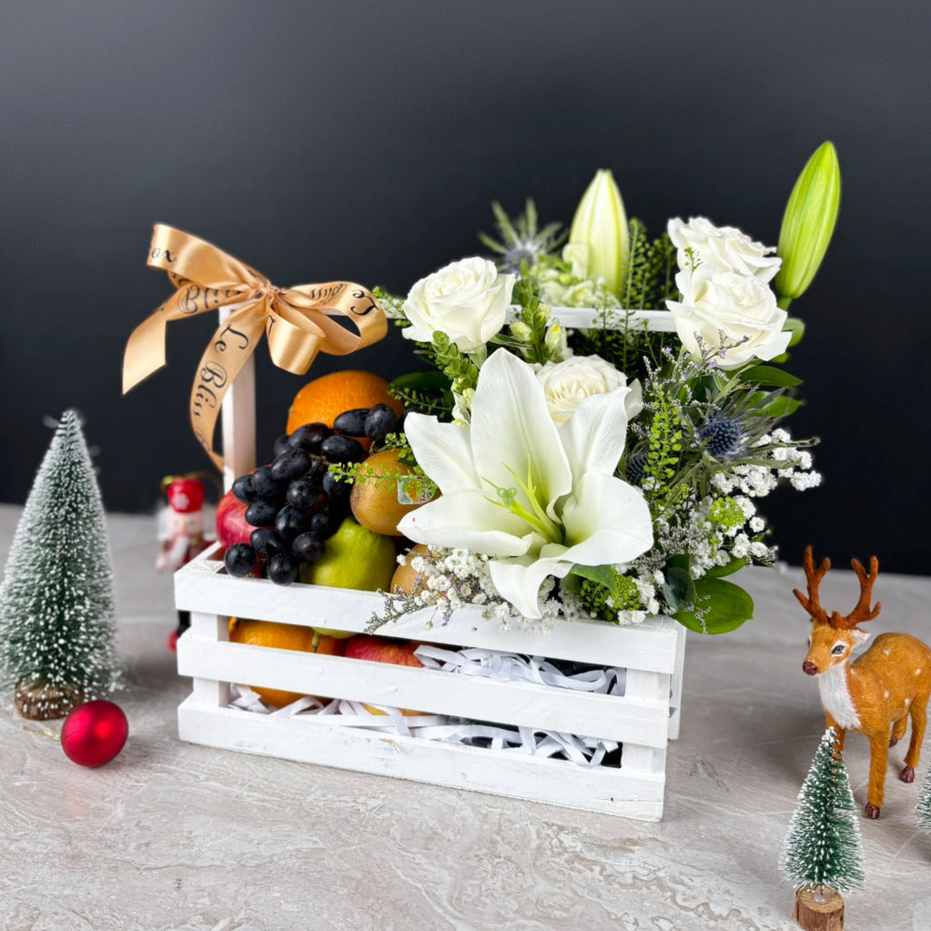 Fruit basket with flowers and decorative items on a table. Blooming White Crate Fruit Parcel | Best Christmas Hamper Jakarta, Tangerang, Cirebon & Surabaya – Le Bliss Bouquet