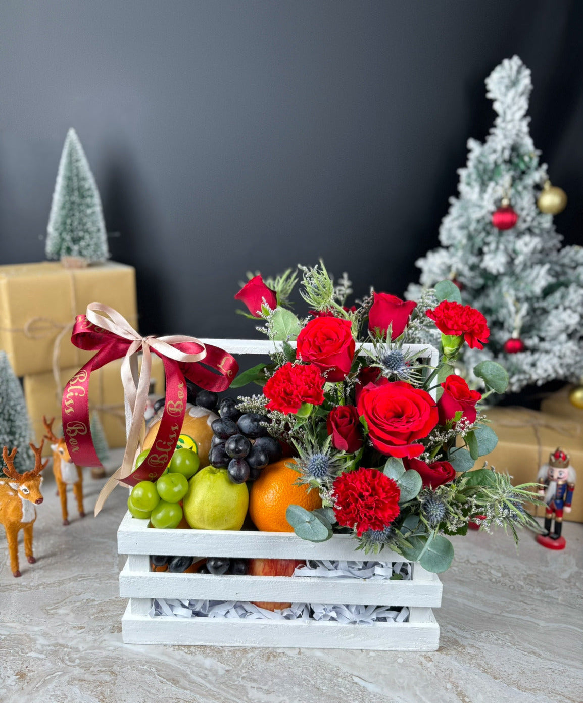 Fruit basket with red roses and decorative ribbons on a dark background. Hamper natal buah dengan bunga by le bliss. Blooming Red Crate Fruit Parcel | Best Christmas Hamper in Jakarta, Tangerang, Cirebon & Surabaya – Le Bliss Box