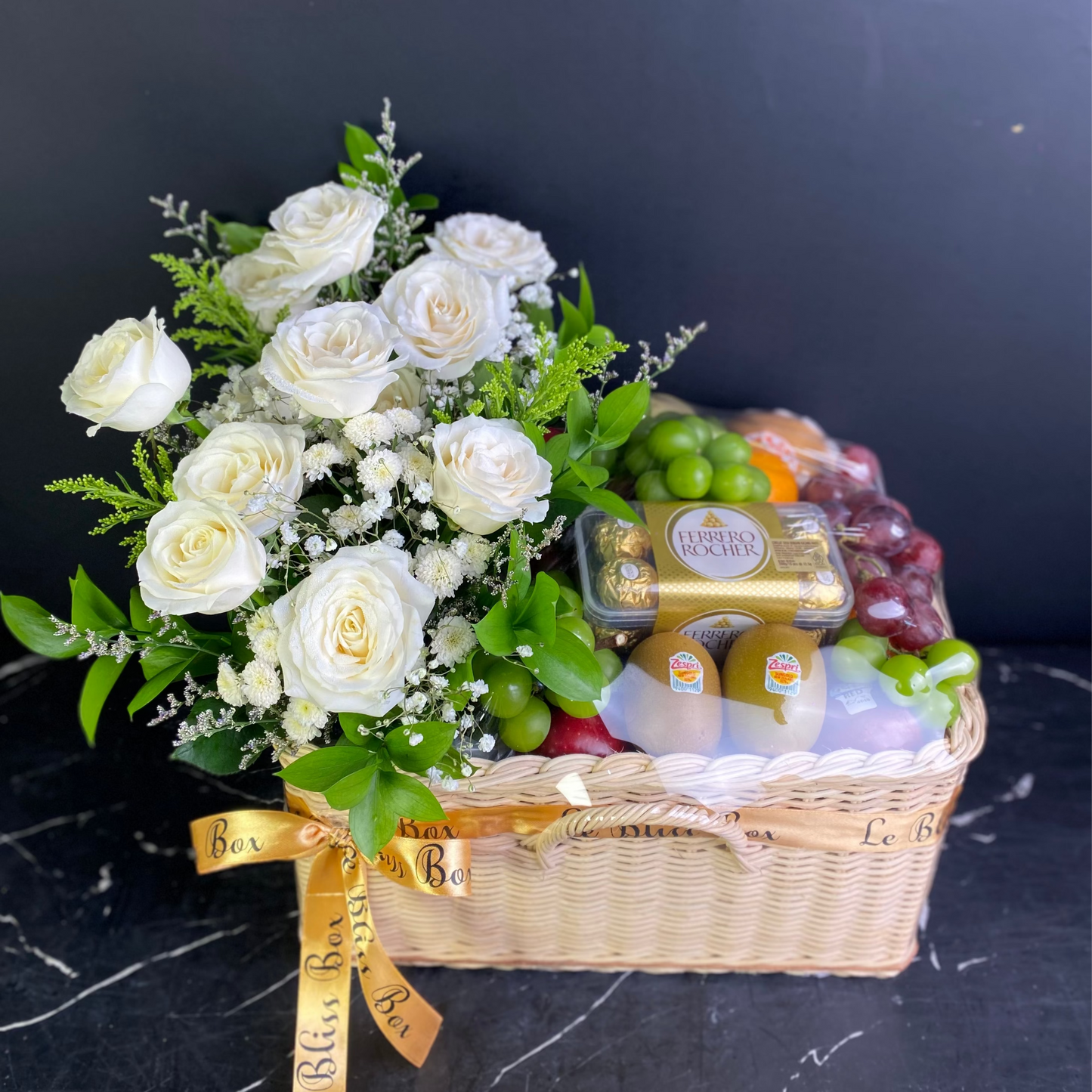 Fruit basket with white roses and a gold ribbon on a dark background. Florist Le Bliss Box parcel buah surabaya, parcel buah jakarta, coklat parcel buah surabaya