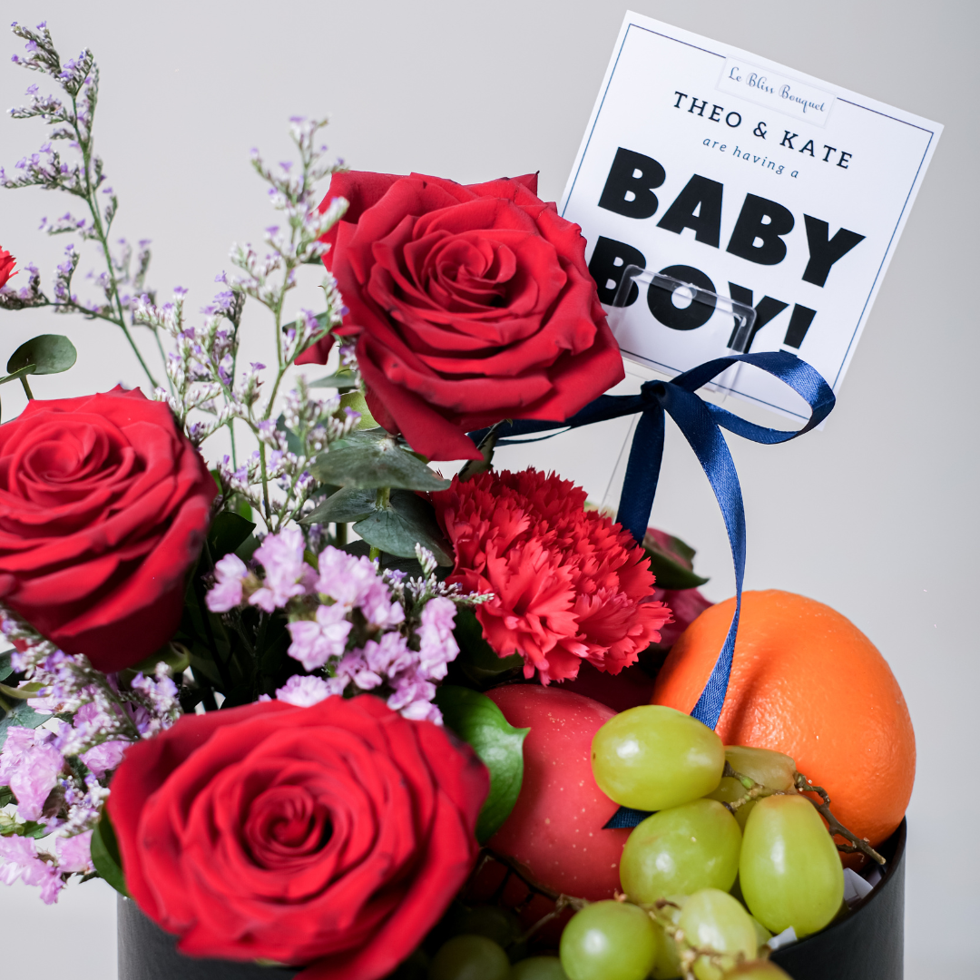 Luxury black flower box with red roses, red carnations, purple fillers, and fresh green grapes, featuring a 'Baby Boy!' announcement card, available for delivery in Jakarta, perfect for a new baby celebration.