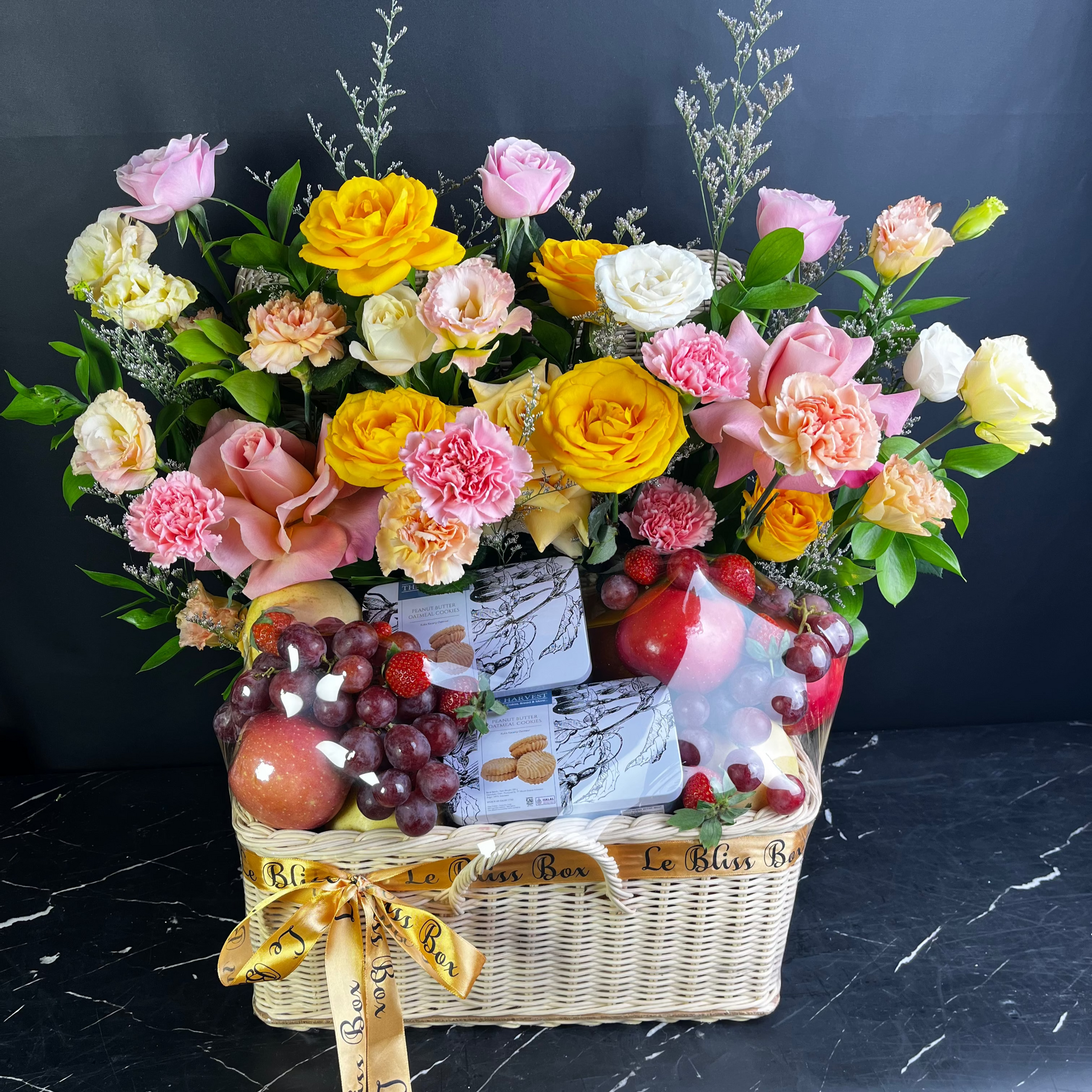 Gift basket with flowers, fruits, and cheese on a dark surface. Grand fruit parcel with harvest cookies by le bliss box. premium parcel buah bunga surabaya, jakarta, cirebon