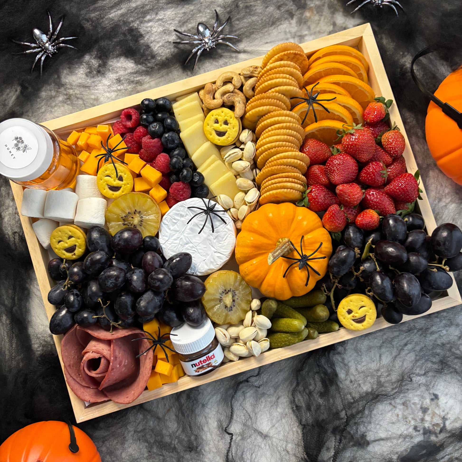 Halloween-themed charcuterie board with various treats and decorations on a dark surface. halloween platter jakarta, halloween platter surabaya by le bliss platter