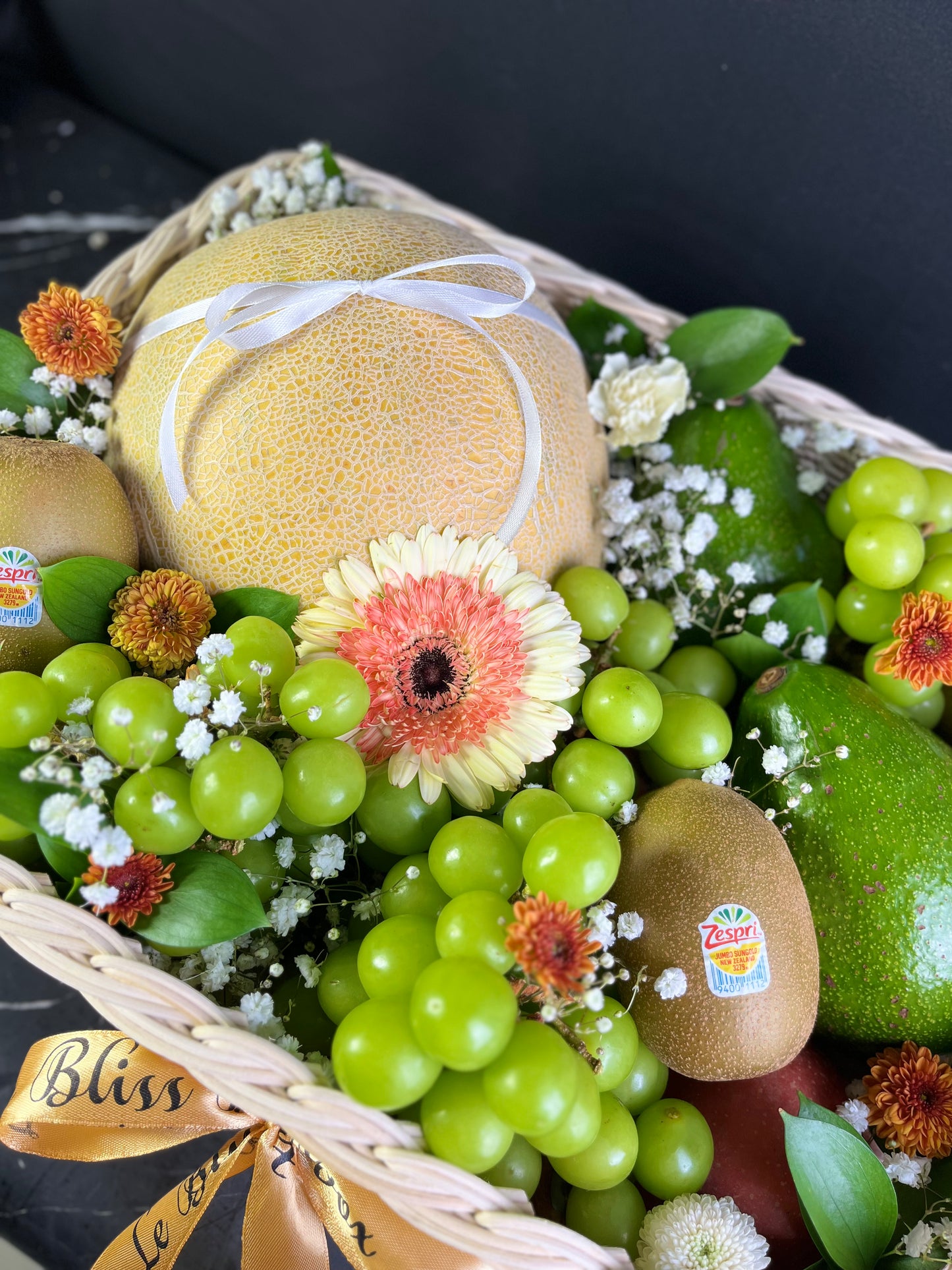 Basket of fruits and flowers with a focus on green apples, kiwis, and grapes.