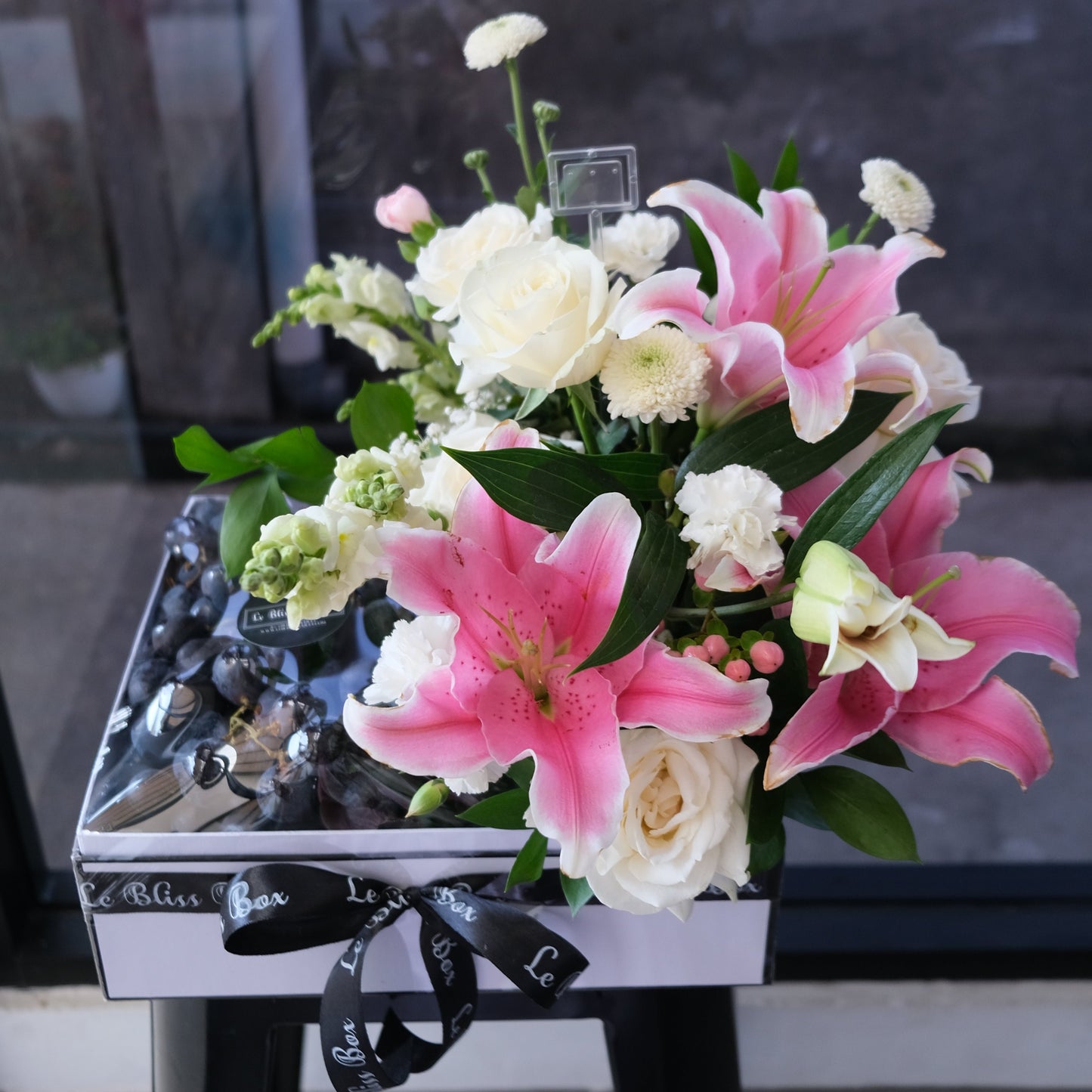 Parcel buah jakarta Autumn Grapes Pink Lily Fruit Box dengan anggur segar dan hiasan bunga lily pink dari Le Bliss Bouquet, ideal untuk hadiah spesial.