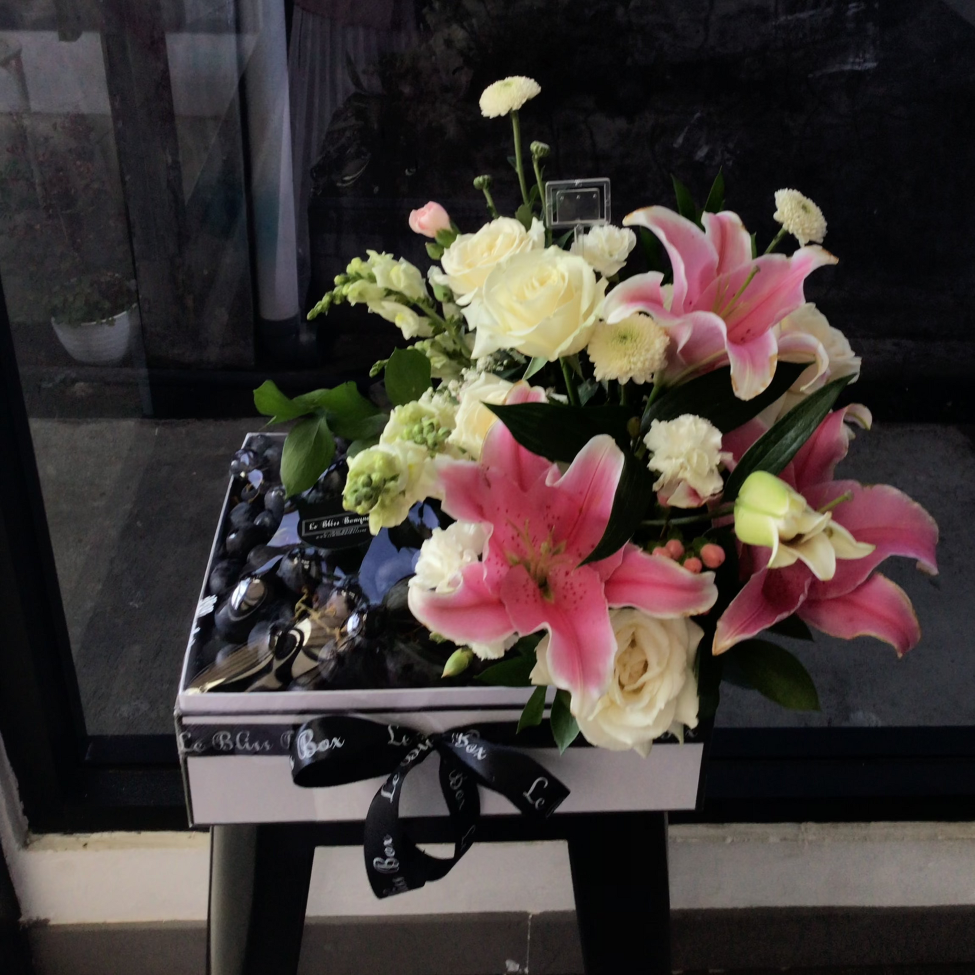 Parcel buah jakarta premium Autumn Grapes Pink Lily Fruit Box dengan anggur segar dan hiasan bunga lily pink dari Le Bliss Bouquet, ideal untuk hadiah spesial.