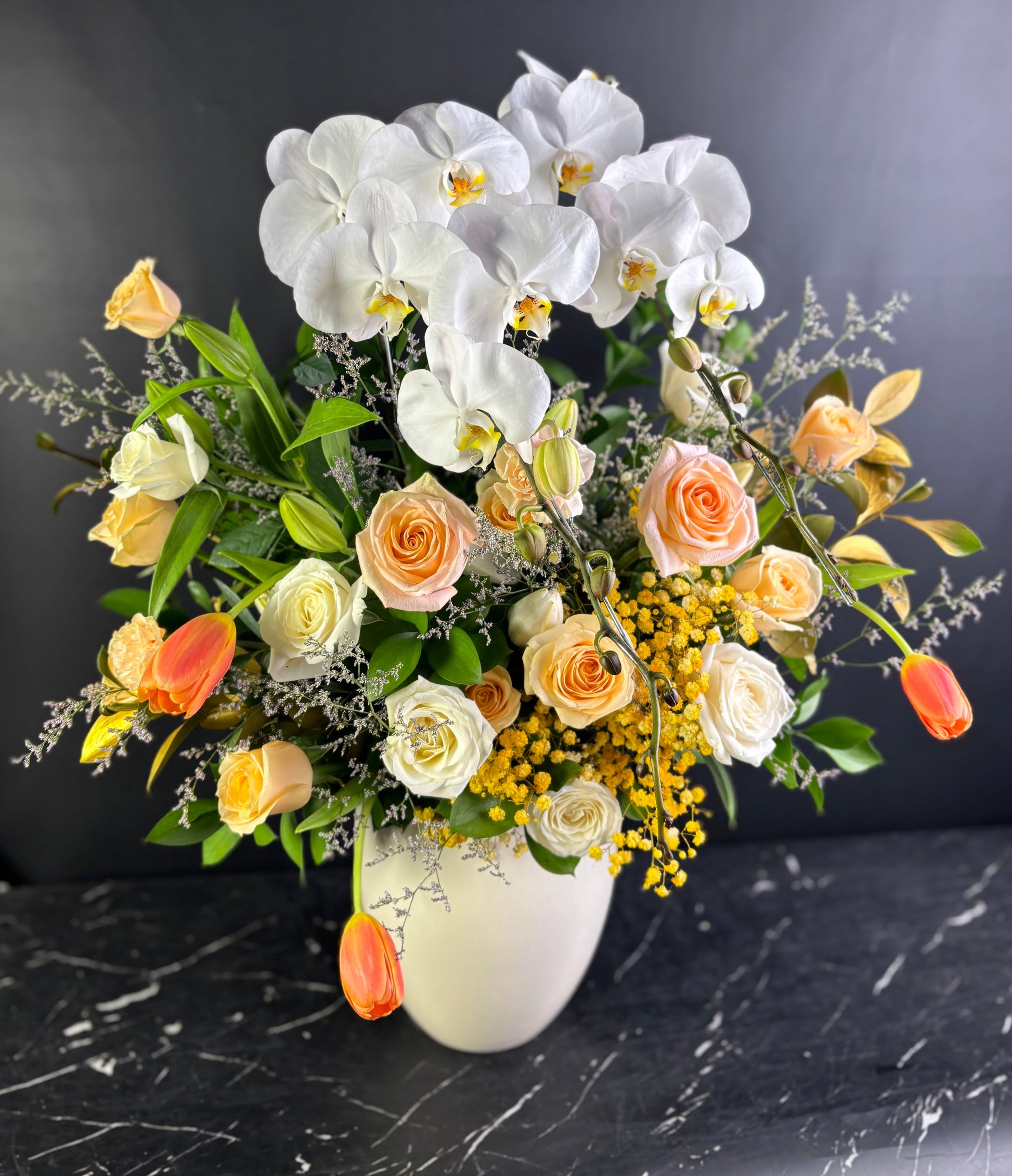 VASE flowers with white orchids, roses, and other flowers in a vase on a dark surface. Florist Jakarta, Surabaya, Cirebon