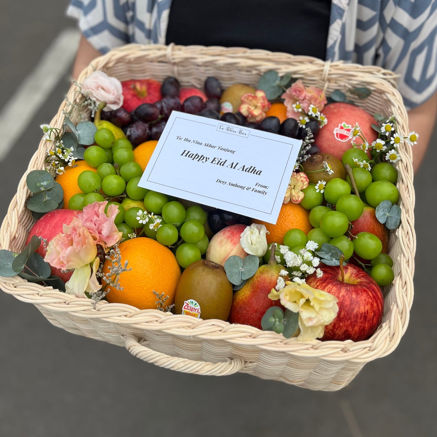 Kotak buah anyaman rotan dengan hiasan bunga segar dari Le Bliss Bouquet, pilihan hadiah elegan dan sehat untuk berbagai acara. Parcel Buah Jakarta - Fruit Hamper Bintaro dan Jakarta | Toko Parcel Buah Mewah by Le Bliss Box
