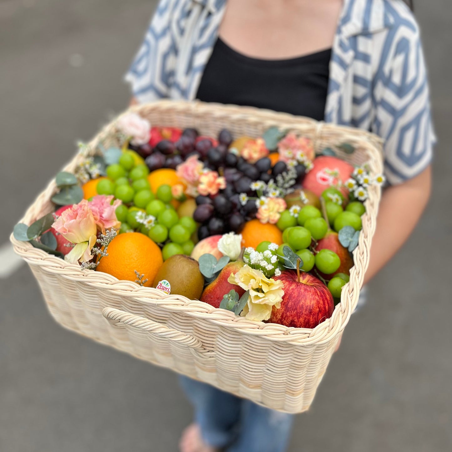 Kotak buah anyaman rotan dengan hiasan bunga segar dari Le Bliss Bouquet, pilihan hadiah elegan dan sehat untuk berbagai acara. Parcel Buah Jakarta - Fruit Hamper Bintaro dan Jakarta | Toko Parcel Buah Mewah by Le Bliss Box
