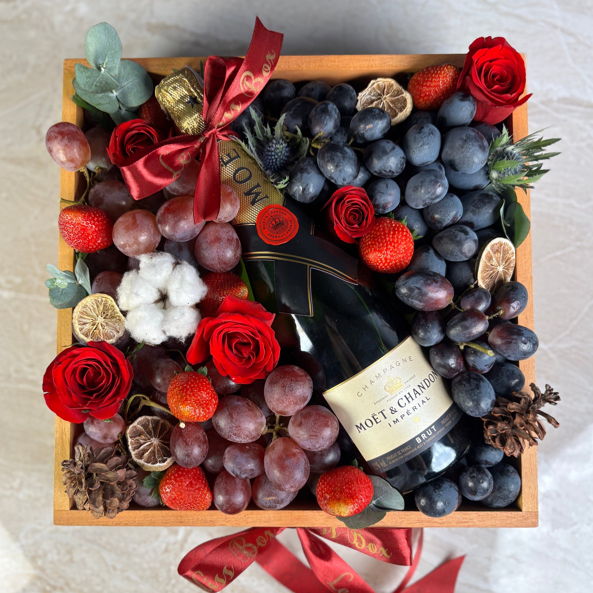 gift hamper box with champagne, grapes, and flowers on a marble surface. Moet Fruit Hamper by Le Bliss Box, moet hamper jakarta, moet hamper surabaya, wine hamper jakarta, champagne hamper jakarta