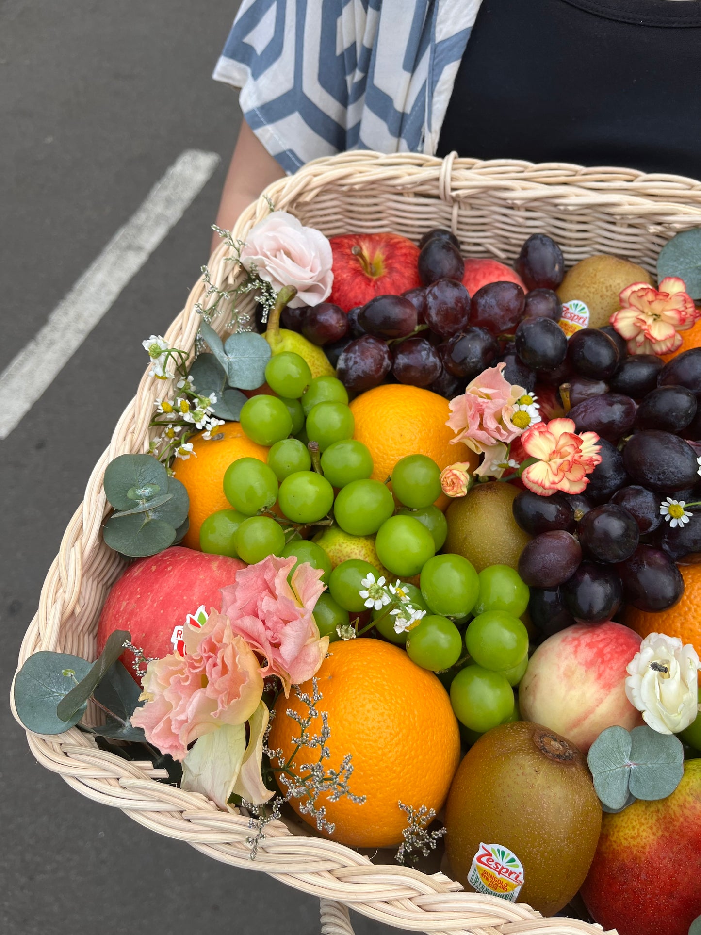 Kotak buah anyaman rotan dengan hiasan bunga segar dari Le Bliss Bouquet, pilihan hadiah elegan dan sehat untuk berbagai acara. Parcel Buah Jakarta - Fruit Hamper Bintaro dan Jakarta | Toko Parcel Buah Mewah by Le Bliss Box