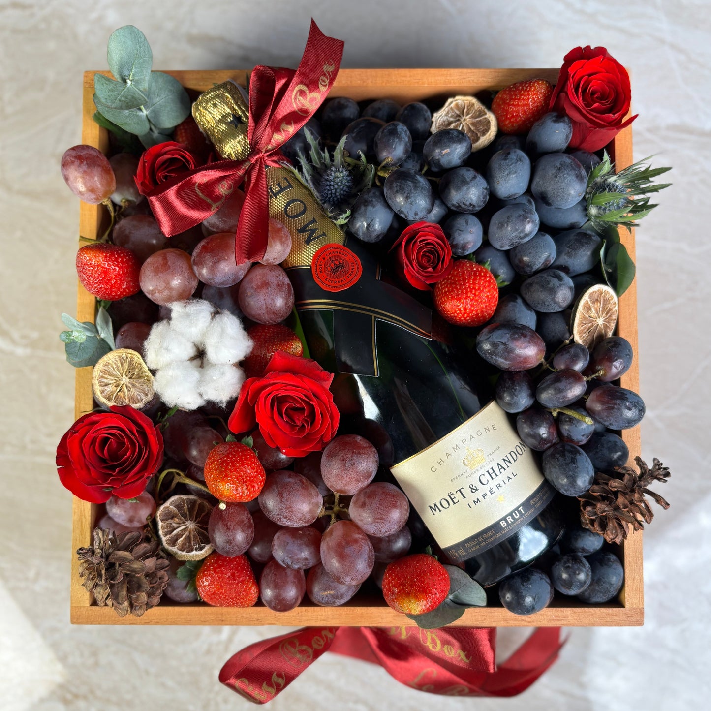 moet hamper jakarta with champagne, grapes, and flowers on a marble surface. Moet Fruit Hamper by Le Bliss Box, moet hamper jakarta, moet hamper surabaya, wine hamper jakarta, champagne hamper jakarta