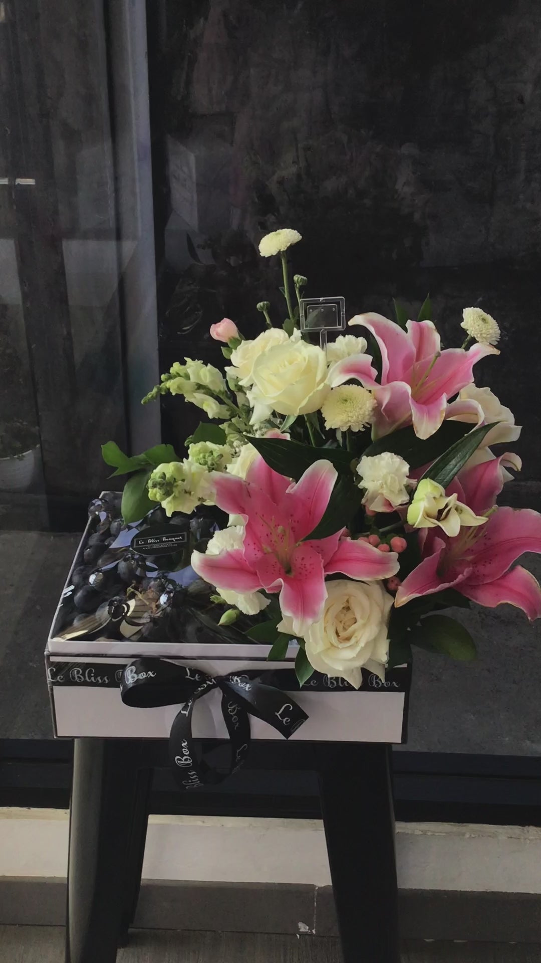 Parcel buah jakarta Autumn Grapes Pink Lily Fruit Box dengan anggur segar dan hiasan bunga lily pink dari Le Bliss Bouquet, ideal untuk hadiah spesial.
