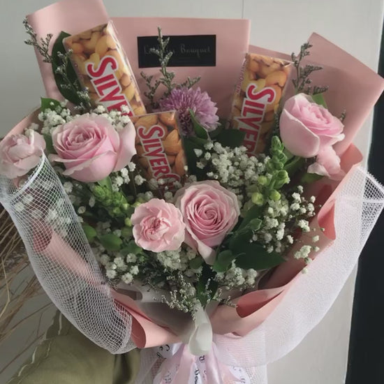 Bouquet of flowers with silverqueen chocolate bars wrapped in paper against a gray background