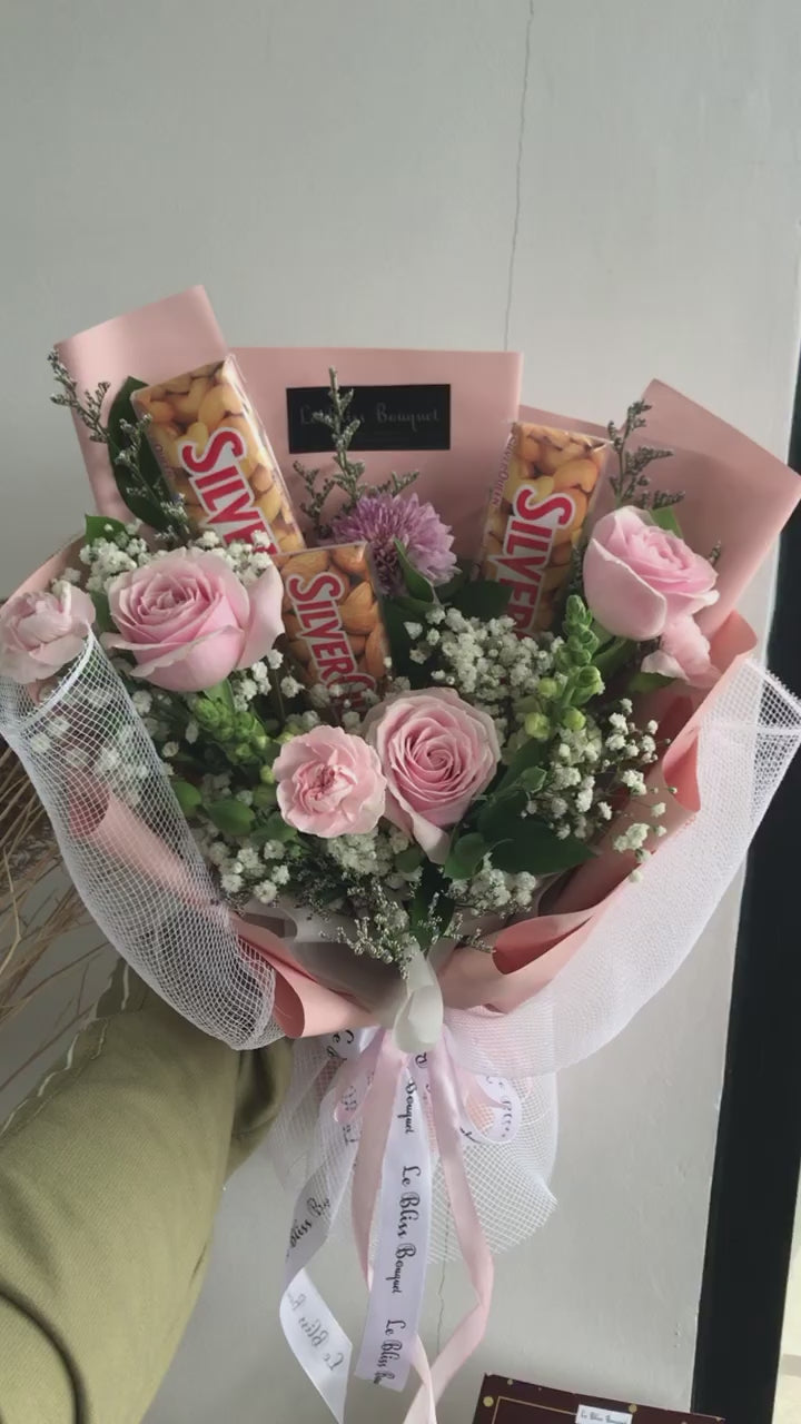 Bouquet of flowers with silverqueen chocolate bars wrapped in paper against a gray background