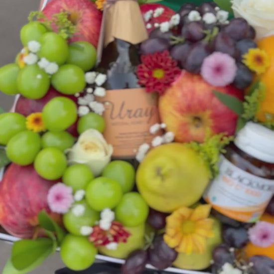 Fruit and flower arrangement with a person wearing a 'Le Bliss Box' apron. Person holding a box of fruits, flowers, and a bottle of wine with 'Le Bliss Box' branding. Parcel buah surabaya, parcel buah jakarta, parcel buah blackmores uray bintaro