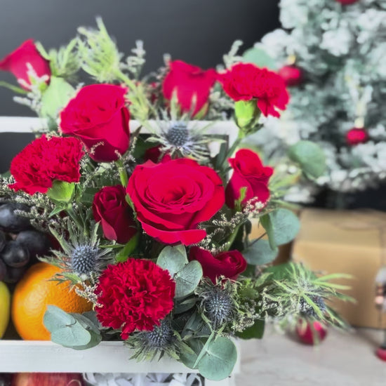 Decorative fruit and flower arrangement in a white crate with Christmas decorations in the background. Blooming Red Crate Fruit Parcel | Best Christmas Hamper in Jakarta & Surabaya – Le Bliss Box