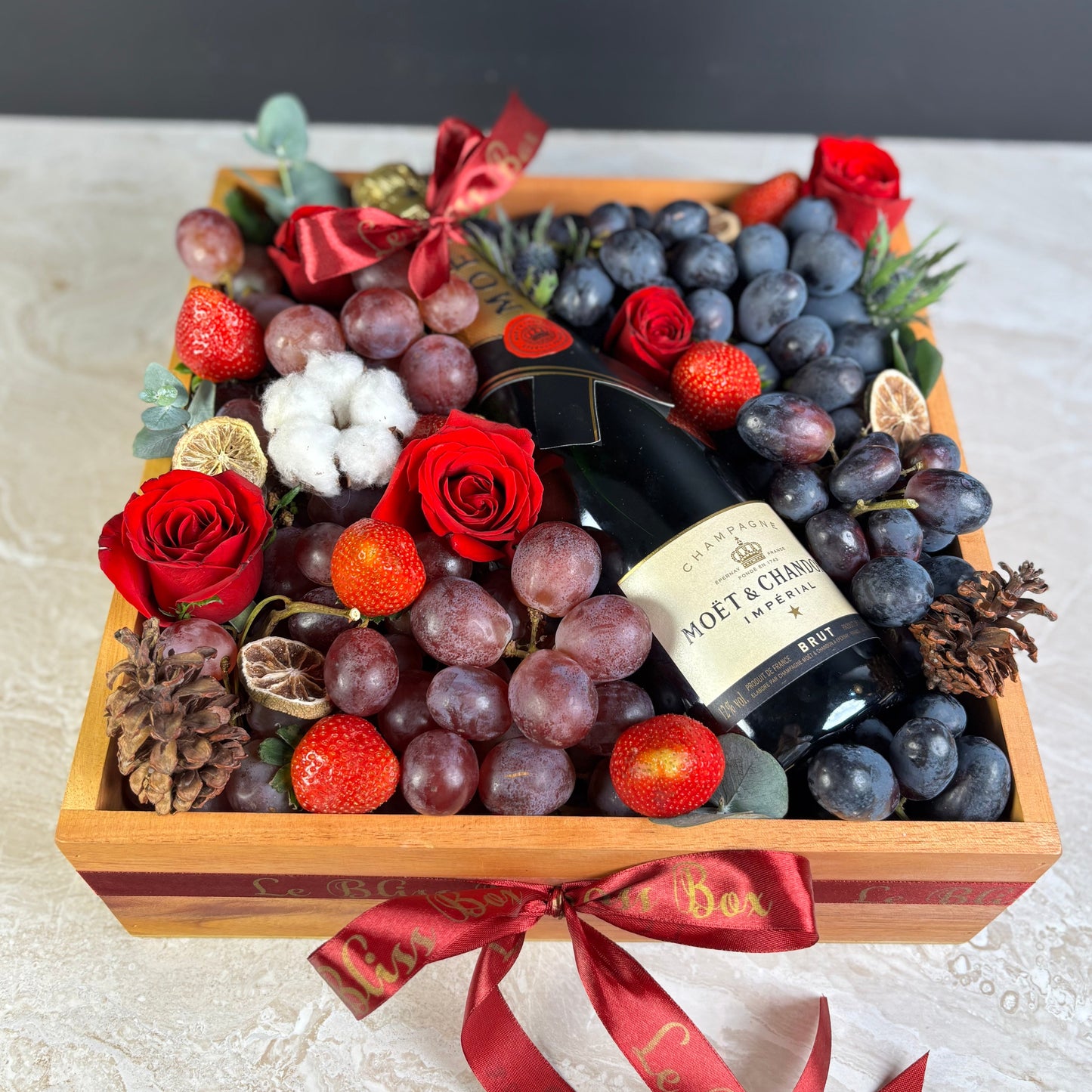 wine hamper jakarta with champagne, grapes, and flowers on a marble surface. Moet Fruit Hamper by Le Bliss Box, moet hamper jakarta, moet hamper surabaya, wine hamper jakarta, champagne hamper jakarta