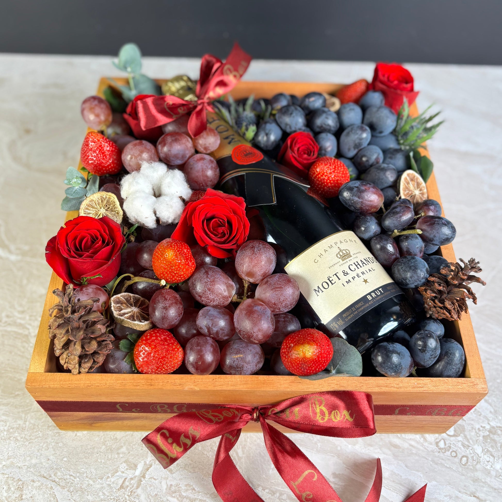 wine hamper jakarta with champagne, grapes, and flowers on a marble surface. Moet Fruit Hamper by Le Bliss Box, moet hamper jakarta, moet hamper surabaya, wine hamper jakarta, champagne hamper jakarta